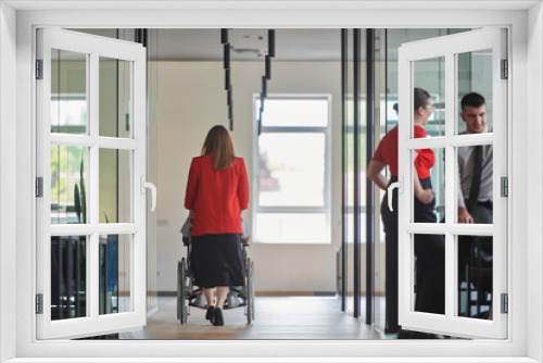 A group of young business people in a modern glass-walled office captures the essence of diversity and collaboration, while two colleagues, including an African American businessman in a wheelchair