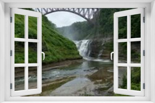 Fototapeta Naklejka Na Ścianę Okno 3D - Scenic view of a bridge crossing a waterfall with a lush green forest in Letchworth State Park