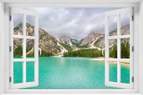 Fototapeta Naklejka Na Ścianę Okno 3D - Braies lake surrounded by pine forests and the rocky ranges of the Dolomites in cloudy day, Italy.