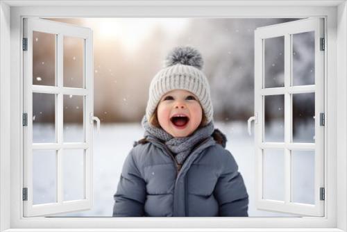 Cute child with happy face wearing a warm hat and warm jacket surrounded with snowflakes. Winter holidays concept.