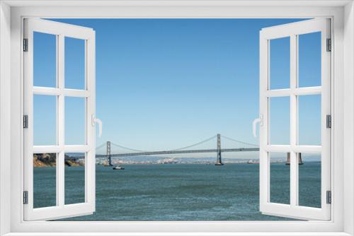 Fototapeta Naklejka Na Ścianę Okno 3D - San Francisco, CA, USA - July 13, 2023: SF-Oakland Bay Bridge lands on Yerba Buena Island under blue sky above blue water. Ships on horizon