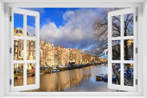 Fototapeta Naklejka Na Ścianę Okno 3D - Cityscape on a sunny winter day - view of the houses and the city canal with boats in the historic center of Amsterdam, The Netherlands