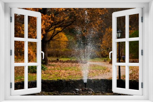 Fototapeta Naklejka Na Ścianę Okno 3D - Idyllic autumn scene featuring a water spout surrounded by vibrant autumn trees