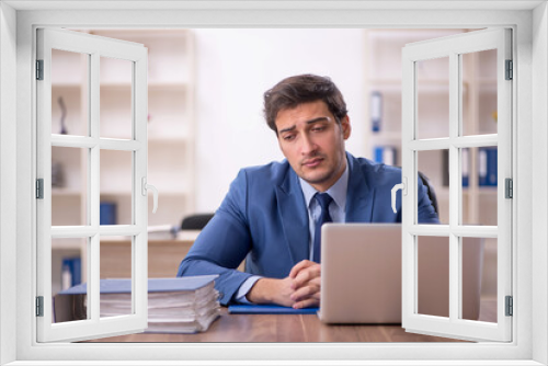 Young male employee and too much work in the office