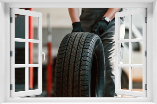 Rolling the wheel. Man is works in the automobile repairing salon