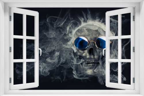 Fototapeta Naklejka Na Ścianę Okno 3D - Old human skull wearing cool blue sunglasses and surrounded by wispy smoke