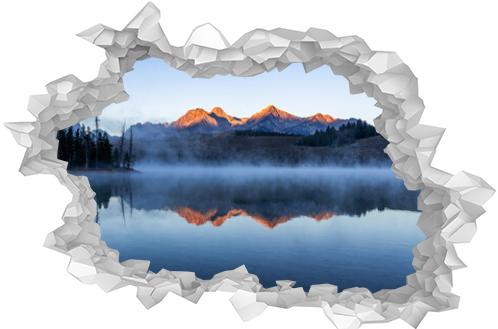 Redfish lake in Idaho in dawn. Calm water covered by mist. Mountains range is reflecting in lake water