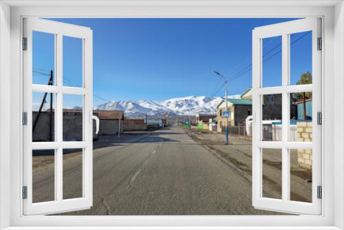 Fototapeta Naklejka Na Ścianę Okno 3D - Northern Mongolia. The morning City is Ulgiy. The houses of the street stretch into the distance, to the snow-capped mountains.