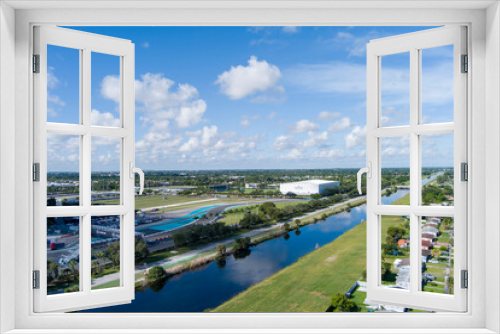 Fototapeta Naklejka Na Ścianę Okno 3D - aerial shot of a river surrounded by lush green trees and grass, homes and parked cars with blue sky and clouds in Miami Florida USA