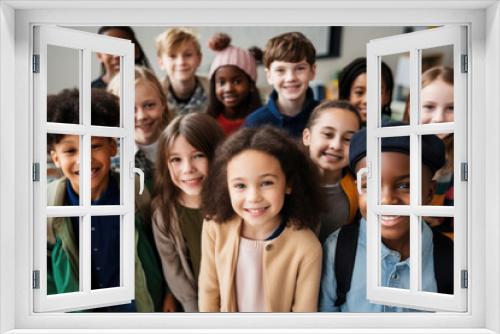 Happy multi-ethnic junior school students standing in classroom, smiling and posing for group portrait together