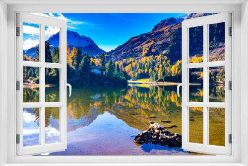 Fototapeta Naklejka Na Ścianę Okno 3D - A view of the Cavlocc lake, in Engadine, Switzerland, and the mountains surrounding it and with autumn colours.
