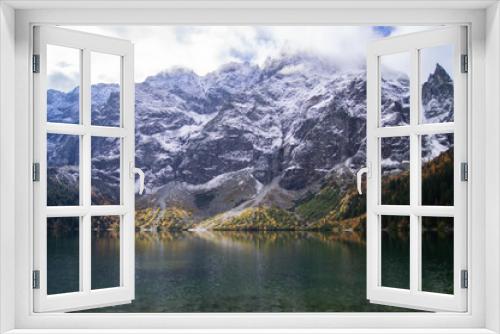 Fototapeta Naklejka Na Ścianę Okno 3D - Scenic capture of Morskie Oko lake during fall. Snowy peaks tower behind, reflecting in clear waters. Vibrant autumn trees surround, creating a serene nature landscape.