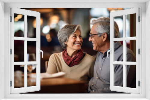 An elderly couple shares a heartfelt moment over dinner, laughing and connecting amidst the warm ambiance of a candlelit restaurant.