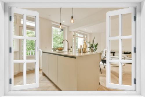 a kitchen and living room in a house with wood floors, white walls, hardwood flooring and large windows