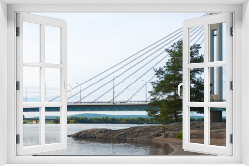 Fototapeta Naklejka Na Ścianę Okno 3D - A calm view of a bridge in the city of Rovaniemi. Traveling north, outdoor recreation, polar circle, tourism in Lapland. Bridge with lumberjack candle. River near the forest. Quiet place for relax