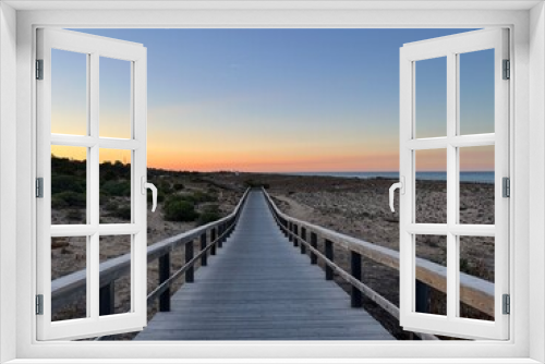 Fototapeta Naklejka Na Ścianę Okno 3D - Boardwalk to the ocean, orange horizon, blue pure sky, no people