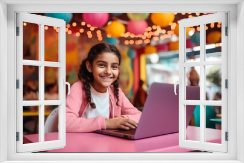 happy indian child girl sitting at table with laptop in cafe