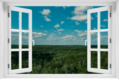 Fototapeta Naklejka Na Ścianę Okno 3D - an aerial shot over the forest with blue skies and white clouds