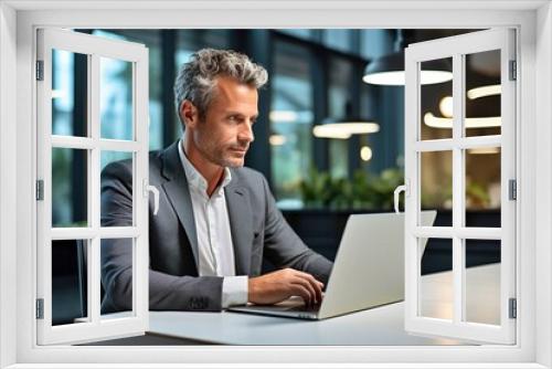 A businessman in serious mode using a laptop. A male professional is seated at his desk at the workplace, strategizing.