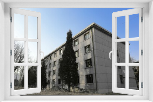 Fototapeta Naklejka Na Ścianę Okno 3D - Exterior of urban gray building with pattern windows and long trees in the front under blue sky