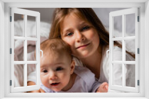 two little girls sisters in New Year's pajamas are lying in bed hugging, top view