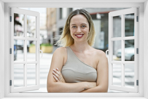 Young blonde woman smiling confident standing with arms crossed gesture at street