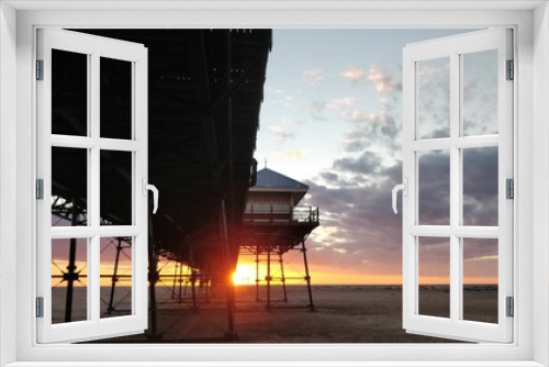Fototapeta Naklejka Na Ścianę Okno 3D - Beautiful view of a sunset at a sandy beach with a pier and a lifeguard tower