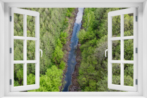 Fototapeta Naklejka Na Ścianę Okno 3D - A small river among the trees in spring, aerial view. Forest river.