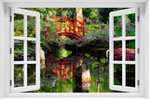 Fototapeta Naklejka Na Ścianę Okno 3D - red bridge reflecting in water with blooming trees in japanese garden in The Hague