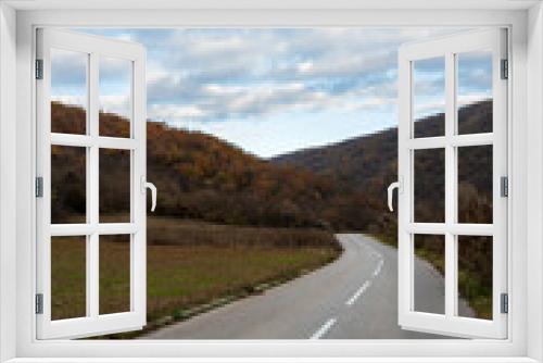 Fototapeta Naklejka Na Ścianę Okno 3D - New country road in autumn.  Country road cutting through green fields in the countryside. Empty asphalt road in rural landscape with dramatic clouds. Open Road.  