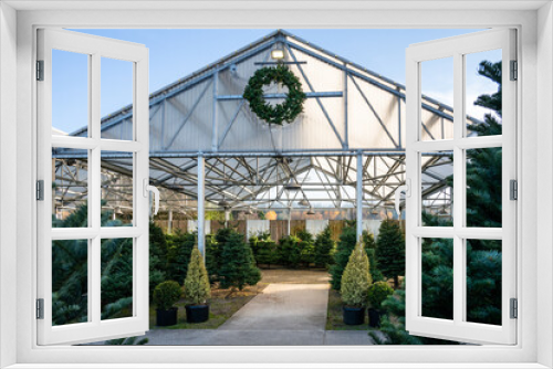 Fototapeta Naklejka Na Ścianę Okno 3D - Covered outdoor Christmas tree lot, wreath hanging over entry, sheared fir trees inside
