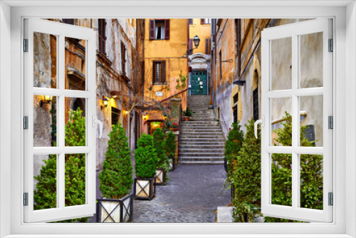 Fototapeta Naklejka Na Ścianę Okno 3D - Rome, Italy. Yard of old street in downtown with antique building and stone stairs. Evening cityscape lamps on walls decorative plants flowerpots