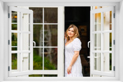 an attractive woman in a white summer dress on the threshold of a country house