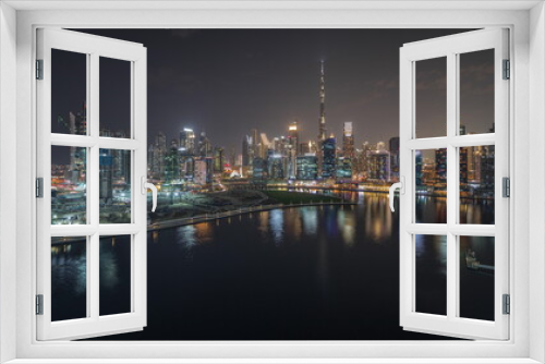 Fototapeta Naklejka Na Ścianę Okno 3D - Panorama showing aerial view to Dubai Business Bay and Downtown with the various skyscrapers and towers night timelapse