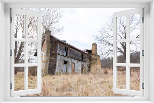 Fototapeta Naklejka Na Ścianę Okno 3D - Rundown rural abandoned house with dead grass and trees in West Virginia