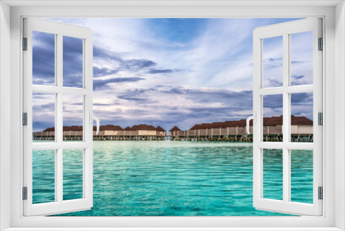 Fototapeta Naklejka Na Ścianę Okno 3D - Scenic view of water villas in Maldives after sunset with turquoise pristine water and dramatic sky 