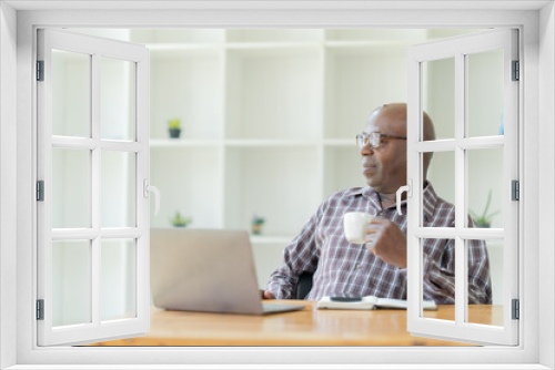 Happy American professional businessman, wearing glasses working on laptop, remote studying using computer looking at screen watching seminar webinar at home office.