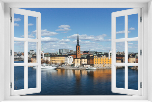 panoramic view of rooftops and view of the town hall tower with many colorful houses in stockholm and water channels huge boat and cloudy sky