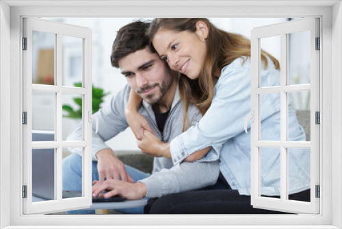 couple embracing while looking at laptop together