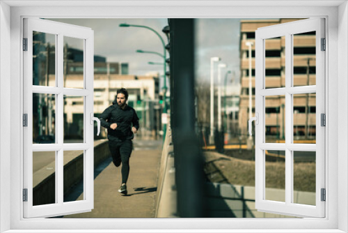 Focused man jogging through the city streets on a sunny day