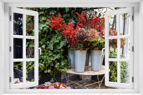 Fototapeta Naklejka Na Ścianę Okno 3D - Ornamental shrubs of red and purple hydrangeas and petunias in large outdoor pots line the border of outdoor cafes and restaurants