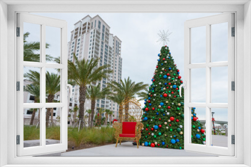 Fototapeta Naklejka Na Ścianę Okno 3D - Florida Christmas Tree and palm trees. Clearwater Florida. Fake, plastic or artificial classic blue spruce for Christmas celebration. Merry Christmas. Happy New Year. Holiday decorations or ornaments