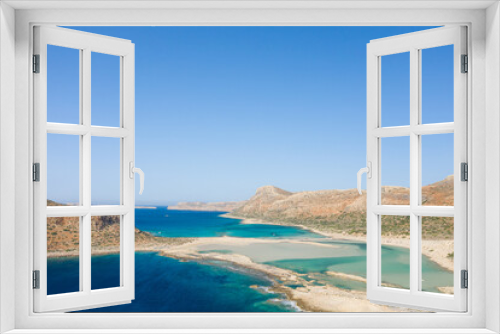 Fototapeta Naklejka Na Ścianę Okno 3D - The sandy beach with pink reflections at the foot of the rocky cliffs, in Europe, Greece, Crete, Balos, By the Mediterranean Sea, in summer, on a sunny day.