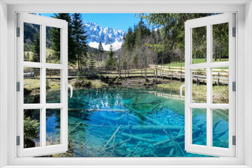Fototapeta Naklejka Na Ścianę Okno 3D - Scenic view of crystal clear waters with submerged logs of Lake Meerauge surrounded by green trees in Boden Valley in Karawanks mountain range in Austria. Turquoise colored pond Austrian Alps