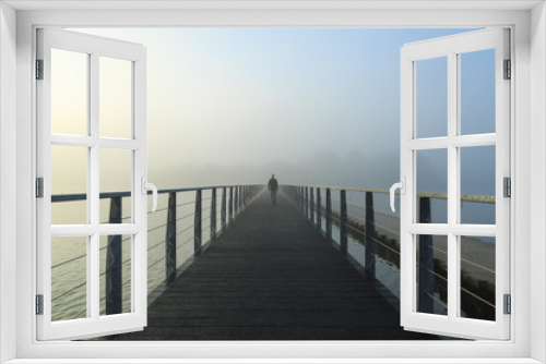 Fototapeta Naklejka Na Ścianę Okno 3D - Man walking on a footbridge into the morning fog.