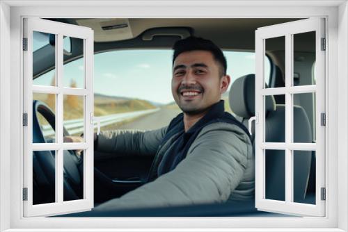 Portrait of smiling young man driving car. behind wheel looking at camera