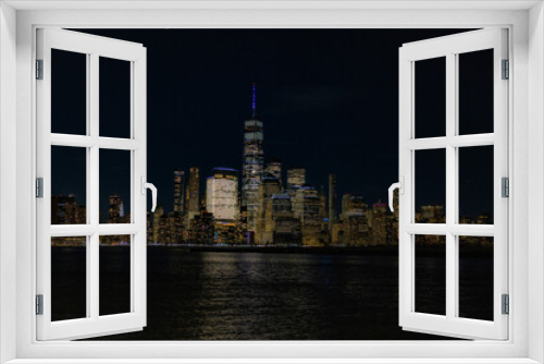 Fototapeta Naklejka Na Ścianę Okno 3D - Stunning view of the New York City skyline at night, beautifully illuminated by lights