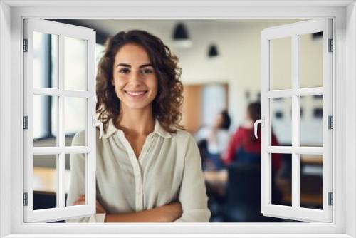 smiling teacher standing in classroom with arms crossed.