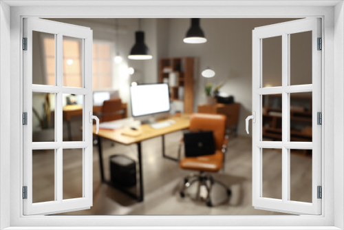 Blurred view of modern office with desks and glowing lamps