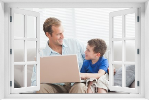 Father and son using laptop on the couch